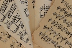 Close-up of vintage sheet music with torn edges, highlighting musical notations and history.